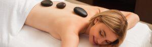 Young woman with hot stones on back on massage table in spa centre